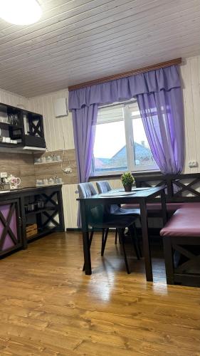 a dining room with a table and purple curtains at Гостинний двір" Живиця" ЧАН in Mizhhirʼʼya