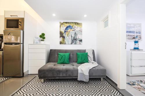 a living room with a couch with two green pillows at Dina Beach House in Nazaré