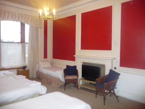 Habitación con 2 camas y chimenea con paredes rojas. en Minto House en Edimburgo