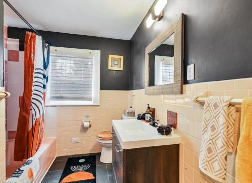 a bathroom with a sink and a toilet and a mirror at Asheville Urban Farmhouse Entire Home 4 mi to DT in Asheville