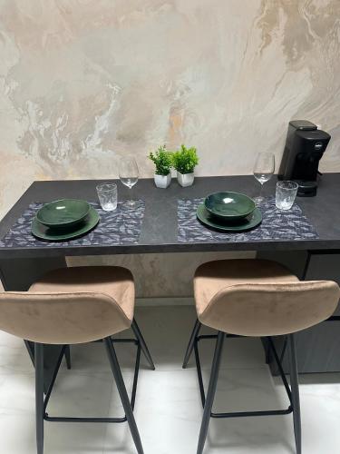 a table with two green plates and wine glasses at Valesium Suite in Lecce