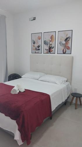 a bedroom with a bed with four pictures on the wall at Apt a 500m da praia do forte in Cabo Frio