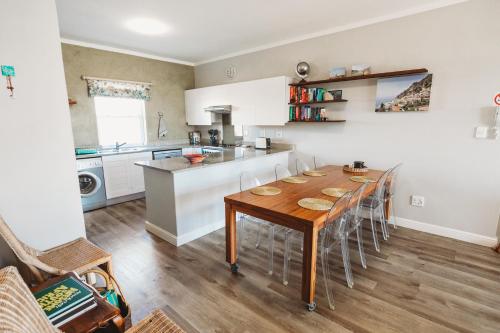 a kitchen with a table and chairs in a room at Restore your Soul, Boulders Beach, Seaforth, Simon's Town in Simonʼs Town