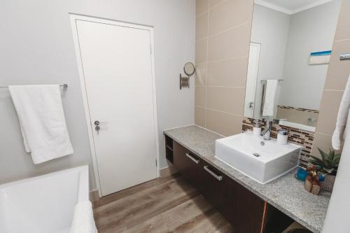 a white bathroom with a sink and a mirror at Restore your Soul, Boulders Beach, Seaforth, Simon's Town in Simonʼs Town