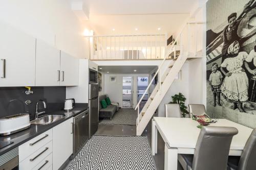 a kitchen with white cabinets and a stairway at Dina Beach House in Nazaré