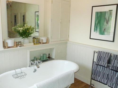 a white bath tub in a bathroom with a mirror at Tinsmiths House in Aylsham