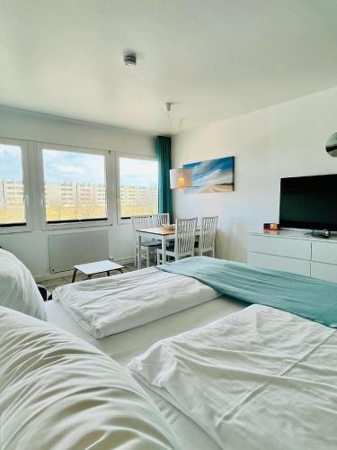 a bedroom with two beds and a table and a television at Ferienwohnung Südanker Fehmarn in Fehmarn