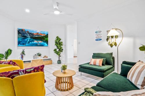 a living room with green and yellow furniture at Villa Ibis Family Home with Pool in Kewarra Beach in Kewarra Beach