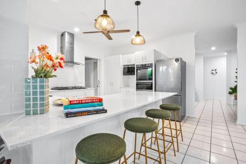 a kitchen with a counter with stools and a refrigerator at Villa Ibis Family Home with Pool in Kewarra Beach in Kewarra Beach