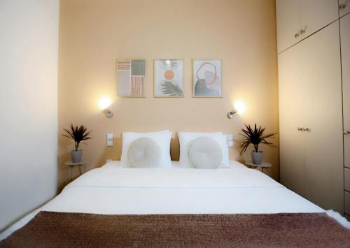a bedroom with a large white bed with two plants at Kamena Elegance in Kamena Vourla