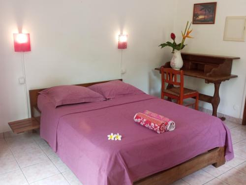 a bedroom with a purple bed and a desk at Ferme auberge Le Rond de Basse Vallée in Saint-Philippe