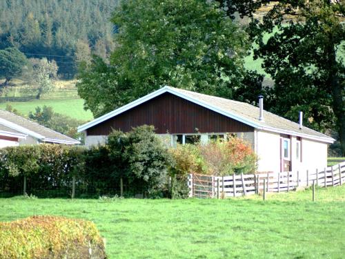 a red and white barn in a field with a fence at Fell Croft in Pooley Bridge