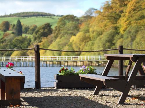 a picnic table and bench next to a body of water at Fell Croft in Pooley Bridge