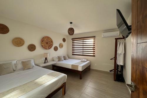 a bedroom with two beds and a flat screen tv at Ixic posada boutique in Zihuatanejo