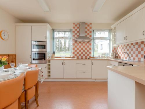 eine Küche mit weißen Schränken und einem Tisch mit Stühlen in der Unterkunft Holiday Home Doonans Cottage by Interhome in Straiton