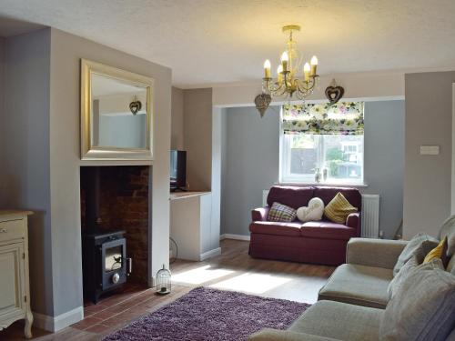 a living room with a couch and a fireplace at Florence Cottage in Pakefield