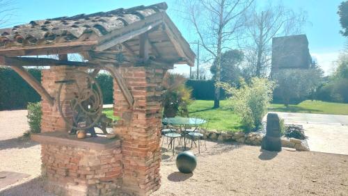 an outdoor brick oven with a table in a garden at Le puits de Jussens in Castelnau-de-Lévis