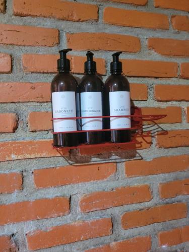 two bottles of wine hanging on a brick wall at Pousada Alto Pirapitinga in Resende