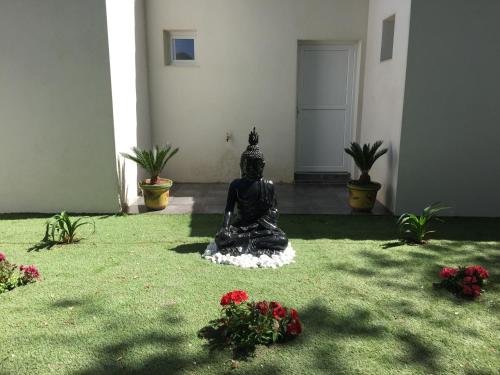 a statue sitting on the grass in a room with flowers at Chambres d'Hôtes Le Mas du Bijou Bleu in Puget-sur Argens