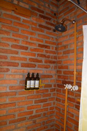 a brick wall with three bottles of wine on a shelf at Pousada Alto Pirapitinga in Resende