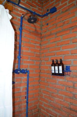 a bathroom with a brick wall with bottles on a shelf at Pousada Alto Pirapitinga in Resende