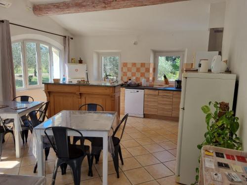 une cuisine avec une table, des chaises et un réfrigérateur dans l'établissement La Fanette, à Montbrison-sur-Lez