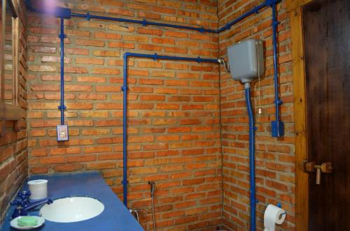 a bathroom with a brick wall with a sink at Pousada Alto Pirapitinga in Resende