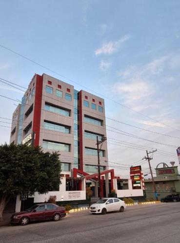 two cars parked in front of a large building at Hotel You Koso in Tijuana