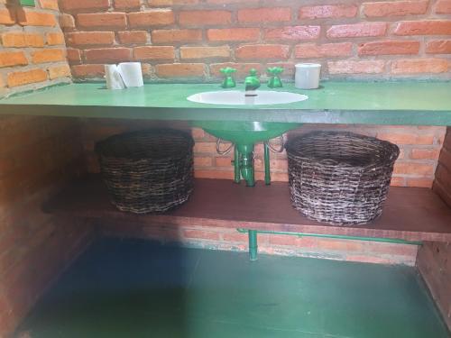 a bathroom with a green sink and two baskets at Pousada Alto Pirapitinga in Resende