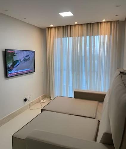 a room with a bed and a television on a wall at Lanzaroti - 204 in Ilhéus