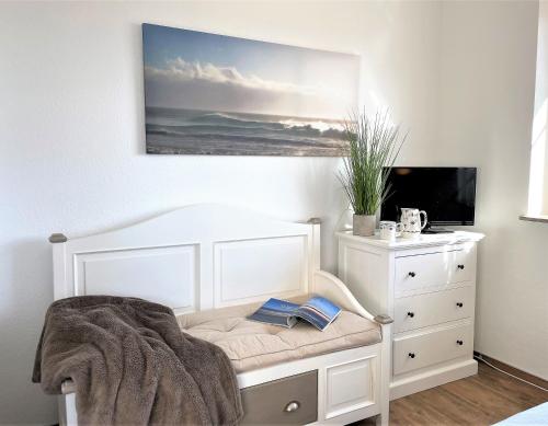 ザンクト・ペーター・オルディングにあるFrida SPO Ferienwohnung Nordsee mit Hundのベッドルーム(白いベッド1台、ドレッサー、テレビ付)