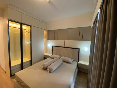 a bedroom with a bed with white pillows and a tub at Sky House BSD in Samporo