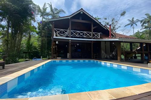 a house with a swimming pool in front of a house at Linda Casa na Praia de Cambury - SP (4) in Boicucanga
