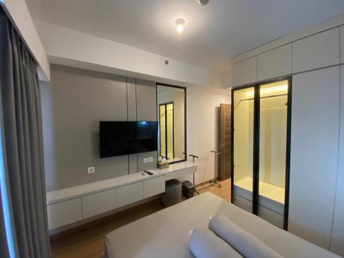 a living room with a tv and a large mirror at Sky House BSD in Samporo
