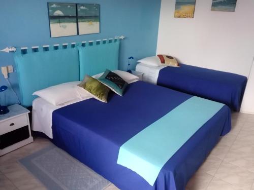 a blue bedroom with a large blue bed with pillows at B&b Margherita in Calasetta