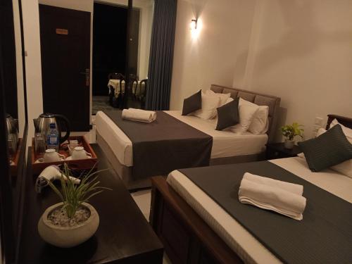 a hotel room with two beds and a table at COCO Rooms in Galle