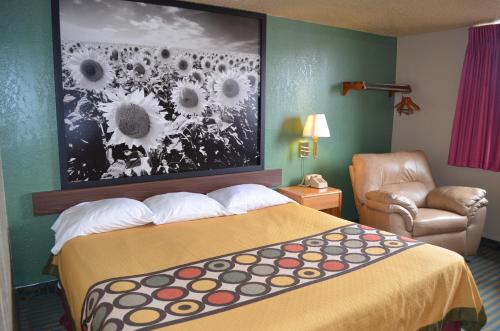 a hotel room with a bed and a painting of sunflowers at Super 8 by Wyndham Devils Lake in Devils Lake