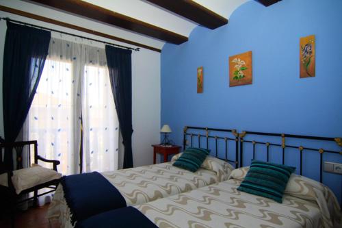 a blue bedroom with a bed with two green pillows at Casa Rural El Lavadero in Bronchales