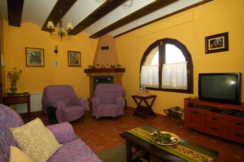sala de estar con muebles de color púrpura y TV en Casa Rural El Lavadero, en Bronchales