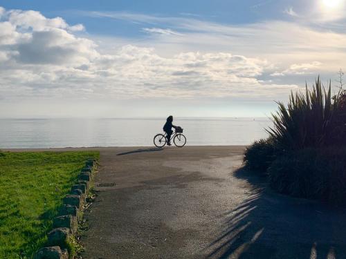 a person riding a bike on a path near the water at The Basket Loft in Newlyn