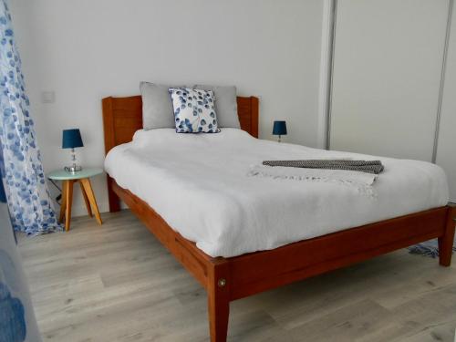 ein Schlafzimmer mit einem Bett mit weißen Laken und blauen Kissen in der Unterkunft Holiday apartments Funchal - Rosemary in Funchal