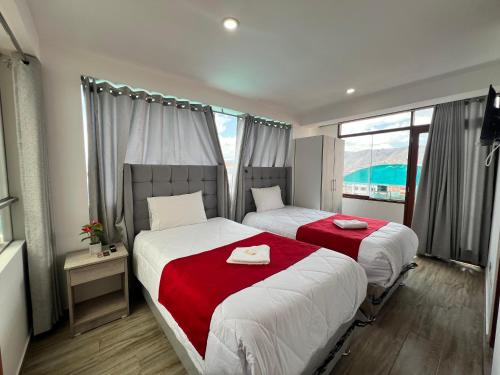 una camera con due letti con coperte rosse di HAYLLI QOSQO Hotel Inn a Cuzco