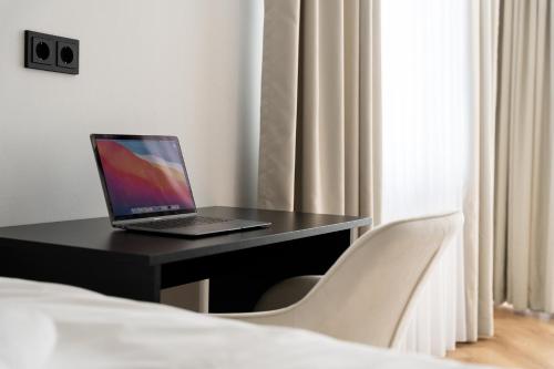a laptop computer sitting on a black desk in a bedroom at ROOMS Bremen -Super Zentrale Studio-Apartments HBF-Messe-ÖVB Arena-City in Bremen
