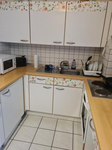 a kitchen with white cabinets and a sink at Private Zimmer in einer Wohngemeinschaft für die Nacht in der Nähe des Flughafens Halle Leipzig in Schkeuditz