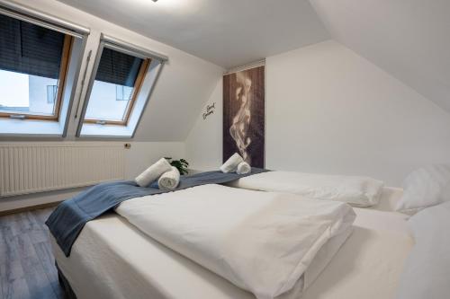 two beds in a bedroom with two windows at Villa Krems Wachau Apartments an der historischen Stadtmauer in Krems an der Donau