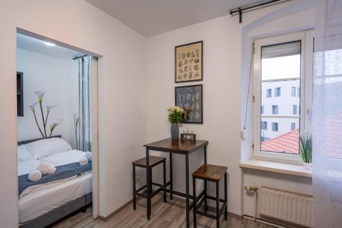 a bedroom with a bed and a table and a window at Villa Krems Wachau Apartments an der historischen Stadtmauer in Krems an der Donau