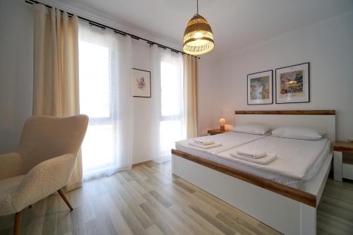 a white bedroom with a bed and a chair at Apartment Emma complex Carpe Diem Balchik in Balchik
