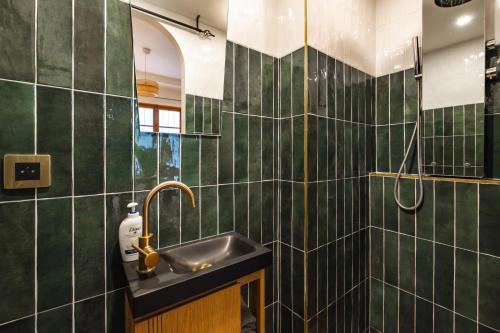 La salle de bains est pourvue de murs carrelés verts et d'un lavabo. dans l'établissement Modern Place in Sacré-Coeur, à Paris