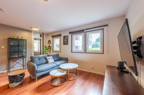 un salon avec un canapé et une télévision dans l'établissement Les Feuillettes, à Annecy