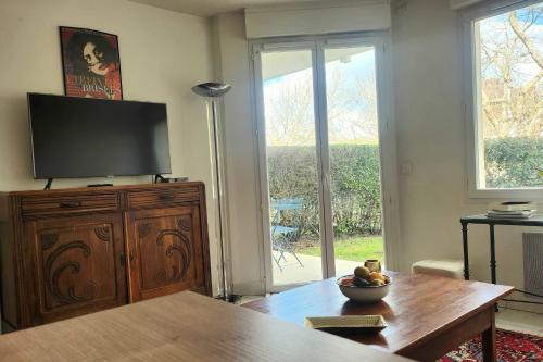 un salon avec une télévision sur un meuble en bois dans l'établissement Nice T2 with garden and terrace in Tourgéville, à Tourgéville